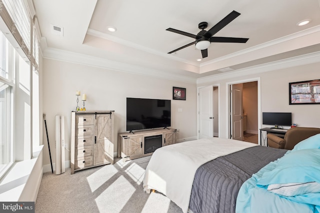 bedroom with a raised ceiling, light colored carpet, visible vents, and ornamental molding