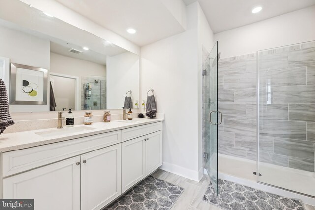 full bathroom with baseboards, visible vents, double vanity, a stall shower, and a sink