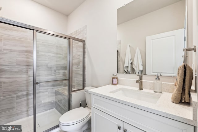 bathroom featuring a shower stall, toilet, and vanity