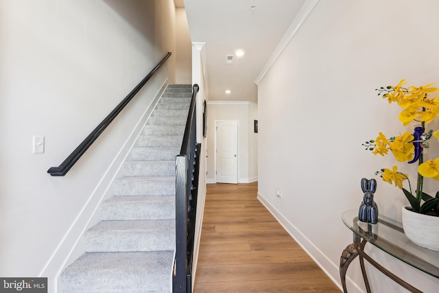 staircase featuring recessed lighting, ornamental molding, baseboards, and wood finished floors