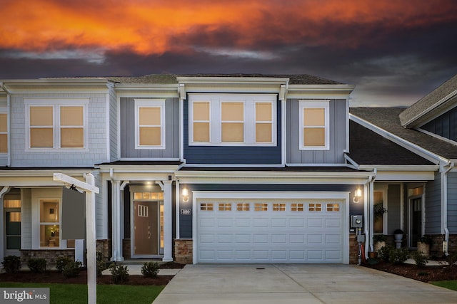 view of front of home with stone siding, board and batten siding, an attached garage, and driveway