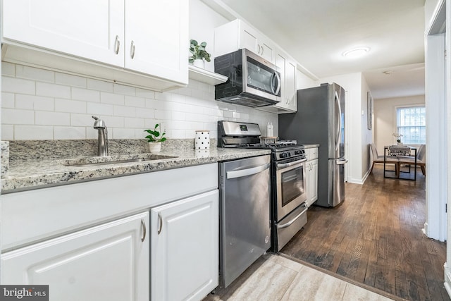 kitchen featuring stainless steel appliances, white cabinetry, and tasteful backsplash