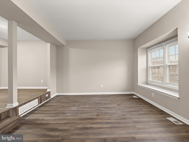 unfurnished room featuring baseboards, visible vents, and wood finished floors