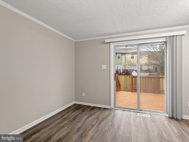 spare room with baseboards, visible vents, wood finished floors, and ornamental molding