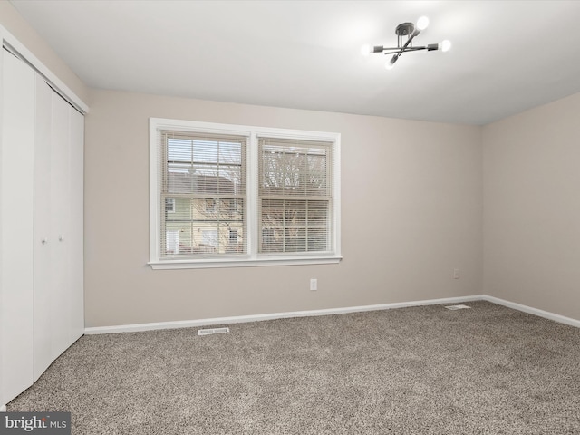 unfurnished bedroom featuring carpet, visible vents, baseboards, and a closet