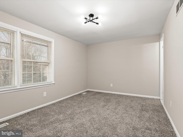 empty room with carpet, visible vents, and baseboards