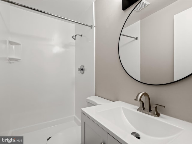 bathroom featuring toilet, a shower, and vanity