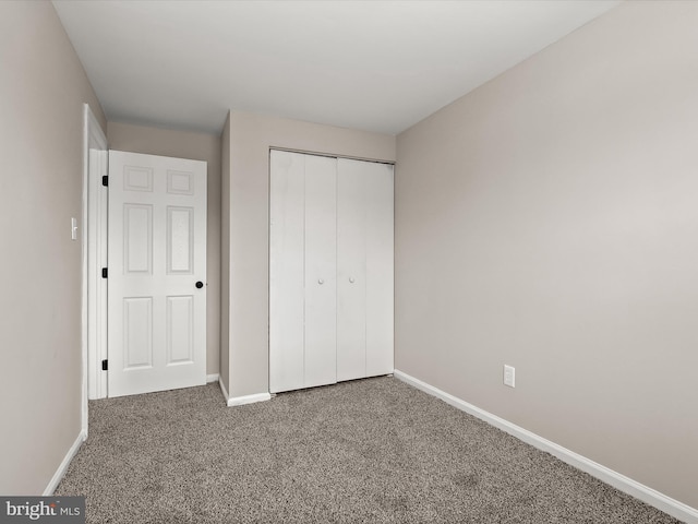 unfurnished bedroom featuring carpet floors, a closet, and baseboards