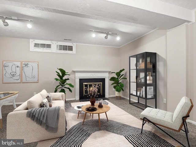 carpeted living room featuring a textured ceiling, crown molding, a glass covered fireplace, and baseboards