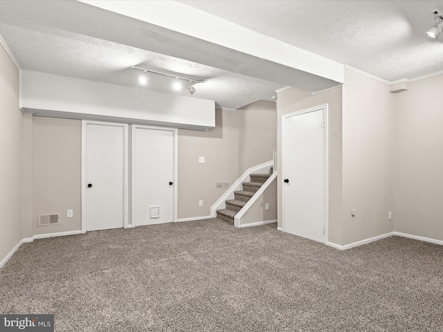 finished below grade area featuring a textured ceiling, stairway, and carpet flooring