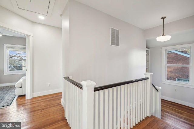 hall with baseboards, an upstairs landing, visible vents, and light wood-type flooring