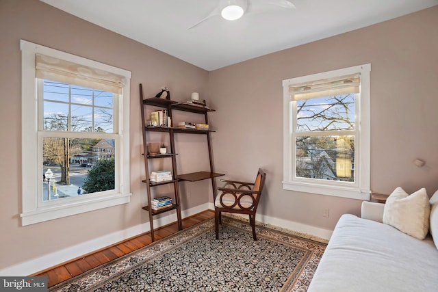 living area with baseboards, plenty of natural light, and wood finished floors