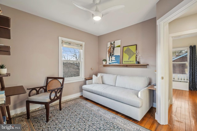 living area with baseboards, ceiling fan, and hardwood / wood-style flooring