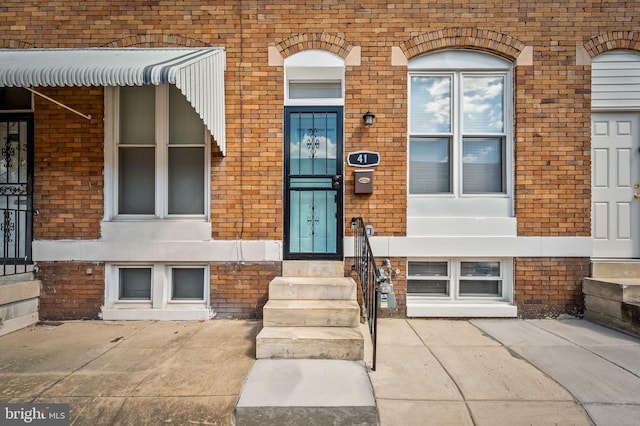 entrance to property featuring brick siding