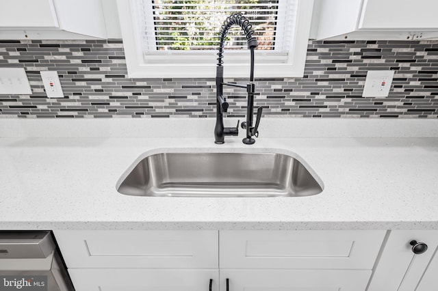 details featuring backsplash, a sink, white cabinetry, and light stone countertops