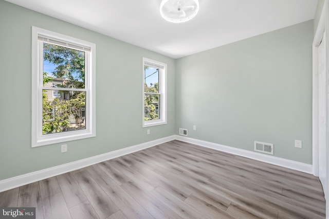 spare room featuring visible vents, baseboards, and wood finished floors