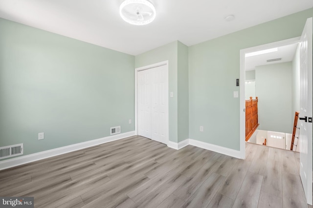 unfurnished bedroom featuring baseboards, visible vents, and wood finished floors