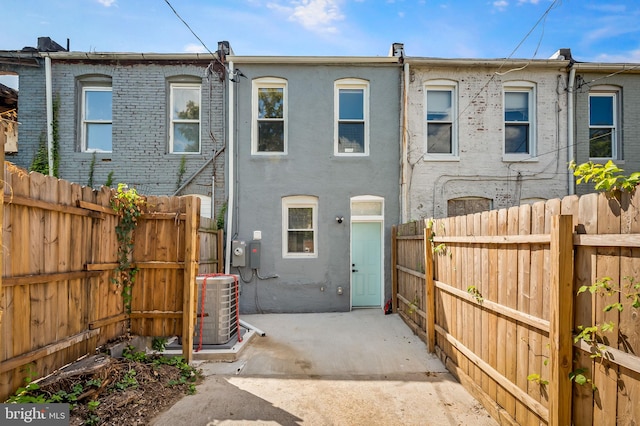 rear view of house with central AC, fence, and stucco siding