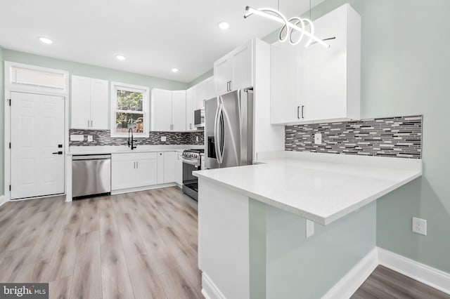 kitchen featuring a peninsula, appliances with stainless steel finishes, light countertops, and white cabinetry