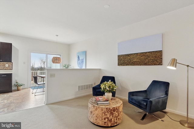 sitting room with baseboards, visible vents, and light colored carpet