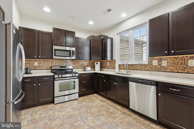 kitchen with stainless steel appliances, backsplash, a sink, and dark brown cabinetry