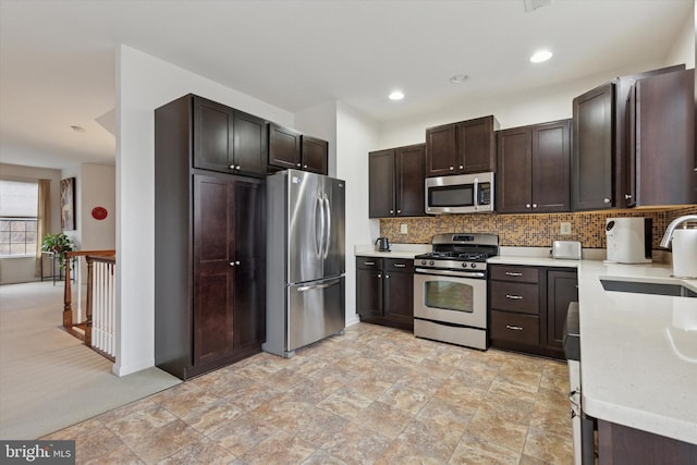 kitchen featuring dark brown cabinetry, a sink, light countertops, appliances with stainless steel finishes, and tasteful backsplash