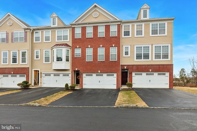 townhome / multi-family property featuring brick siding, driveway, and an attached garage