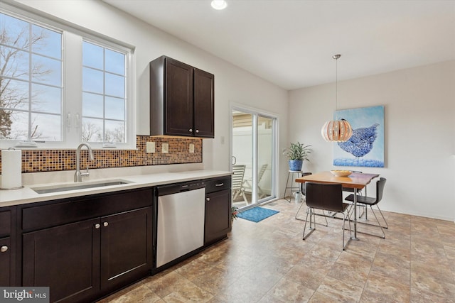 kitchen with dark brown cabinetry, decorative backsplash, dishwasher, light countertops, and a sink