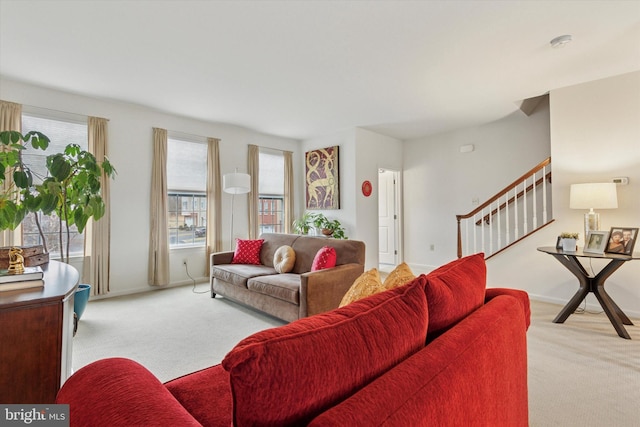 carpeted living area featuring baseboards and stairs