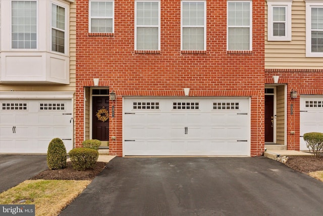 multi unit property with a garage, aphalt driveway, and brick siding