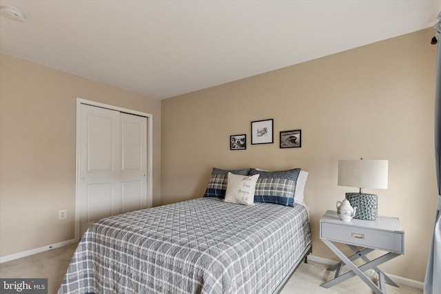 carpeted bedroom with a closet and baseboards