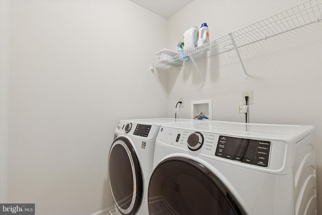 clothes washing area with washing machine and dryer, laundry area, and baseboards