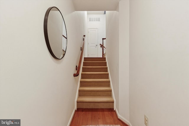 stairs with baseboards, visible vents, and wood finished floors