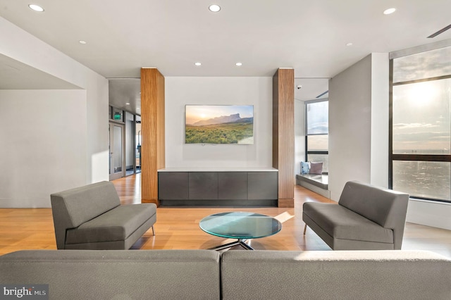 living area with expansive windows, light wood-type flooring, and recessed lighting