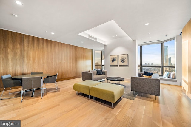 living room with wood walls, floor to ceiling windows, and light wood finished floors