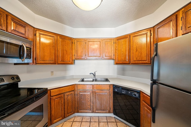 kitchen featuring light countertops, appliances with stainless steel finishes, brown cabinetry, and a sink