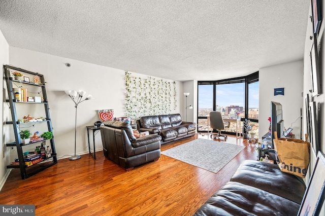 living room featuring a wall of windows, a textured ceiling, baseboards, and wood finished floors