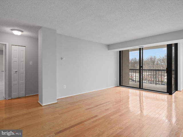 unfurnished room with a textured ceiling, wood finished floors, and baseboards