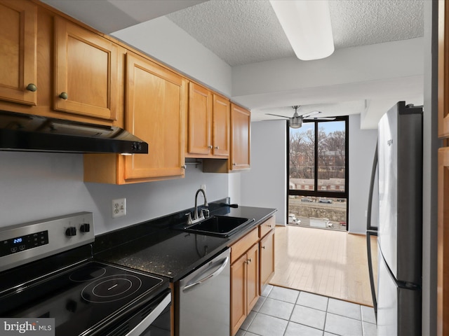 kitchen with ceiling fan, stainless steel appliances, a textured ceiling, under cabinet range hood, and a sink