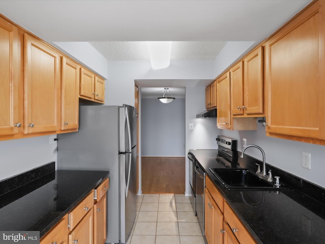 kitchen featuring light tile patterned floors, stainless steel appliances, a textured ceiling, under cabinet range hood, and a sink