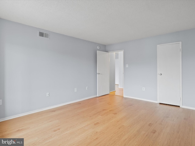 unfurnished bedroom featuring baseboards, visible vents, a textured ceiling, and light wood finished floors