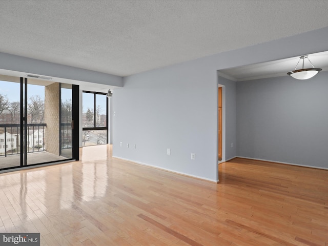 spare room with visible vents, baseboards, light wood-style flooring, and a textured ceiling