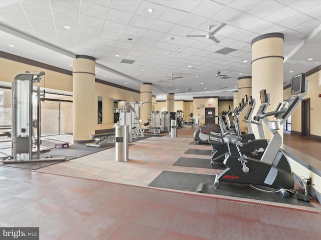 exercise room with a paneled ceiling and ornate columns