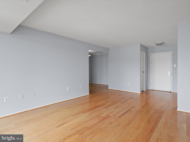 empty room with a textured ceiling and wood finished floors