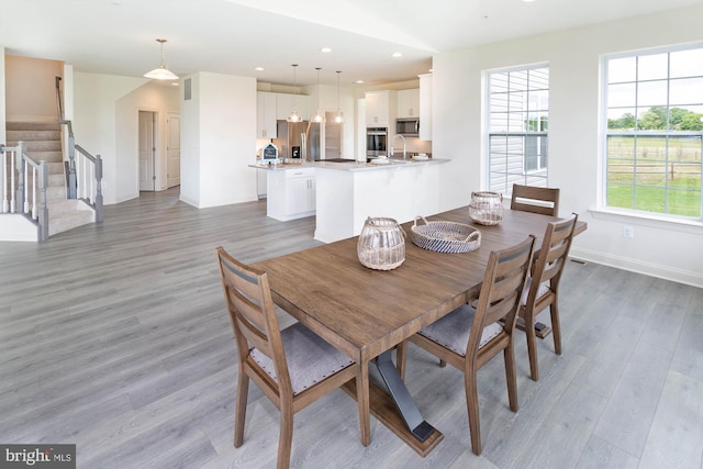 dining space with light wood-style flooring, stairway, baseboards, and recessed lighting