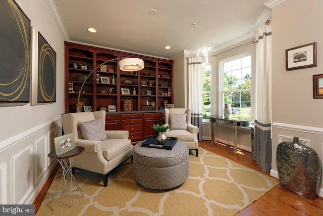 sitting room featuring a decorative wall, recessed lighting, wood finished floors, ornamental molding, and wainscoting