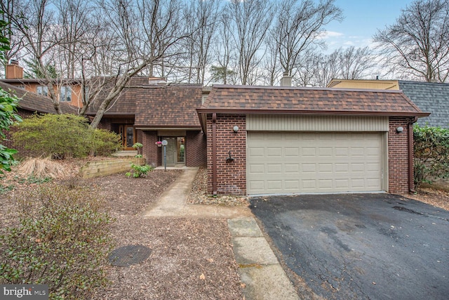 view of front of property with roof with shingles, brick siding, driveway, and mansard roof