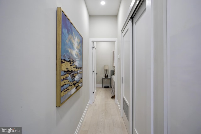 hallway with light wood-type flooring and baseboards