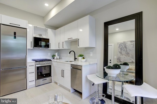 kitchen with stainless steel appliances, white cabinets, a sink, and modern cabinets