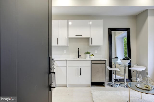 kitchen featuring light wood-style flooring, a sink, white cabinetry, dishwasher, and modern cabinets